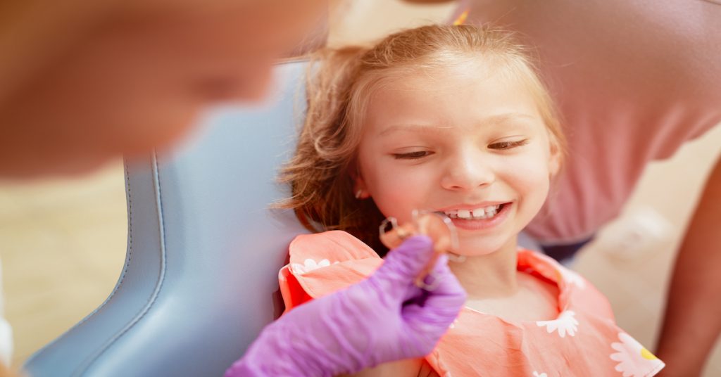 Plano detalle de una ortodoncista mostrando un aparato dental removible a una paciente